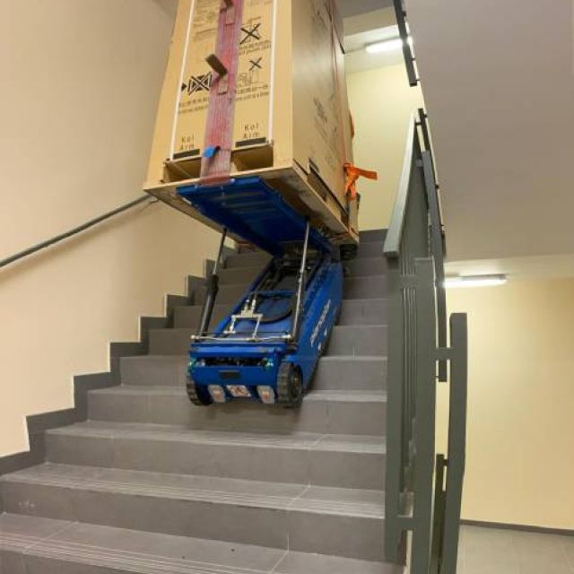 equipo de transporte de pianos de iprom moviendo un piano vertical por una escalera.