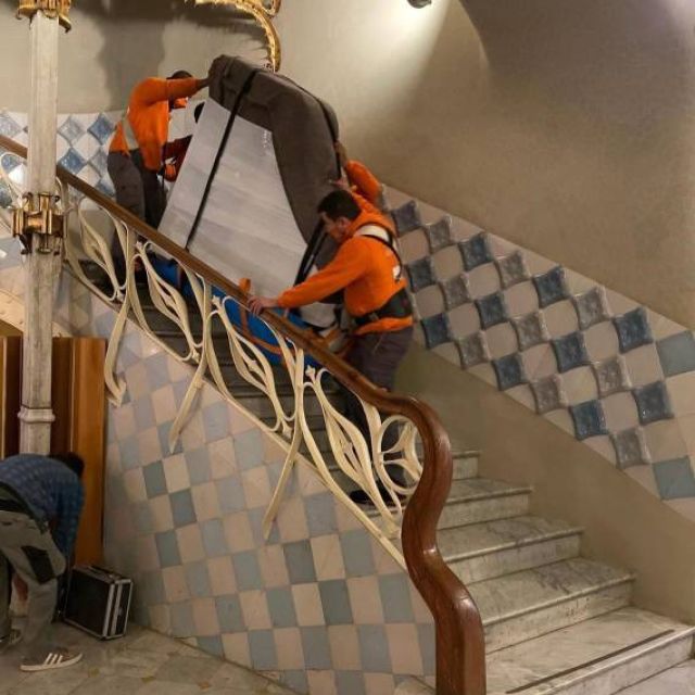 equipo subiendo piano de cola por las escaleras circulares para ser colocado en sala de musica