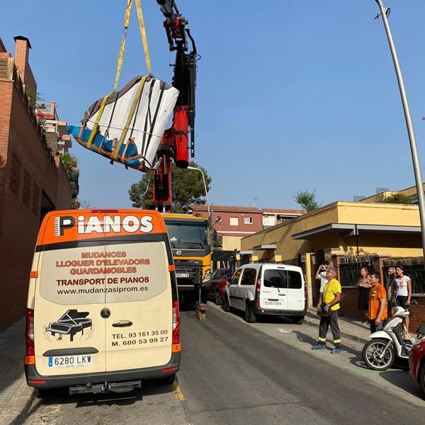 Camion grua elevando un piano para pasar el muro en traslado de piano