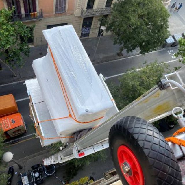Piano subioendo por plataforma elevadora al destino del cliente, bien asegurado y embalado para no sufrir ningún daño