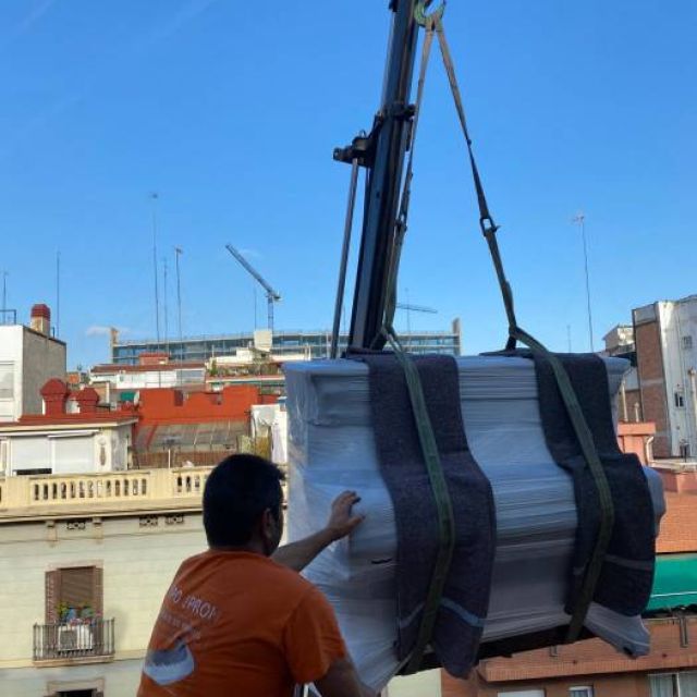 personal de trasporte de piano recogiendo el pieno elevado mediante grua especial para traslado de pianos a gran altura