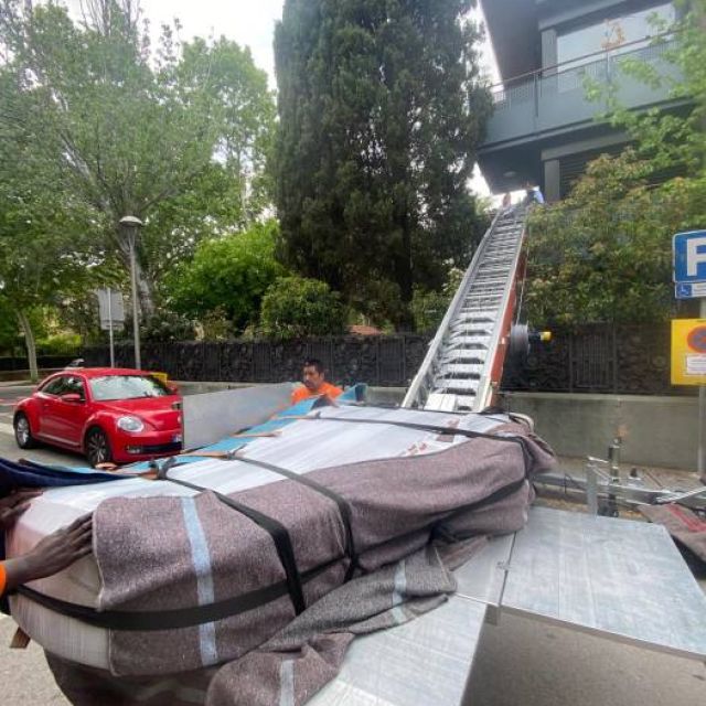 equipo recogiendo un piano de cola despues de ser descendido de la vivienda mediante una plataforma elevadora especial para pianos