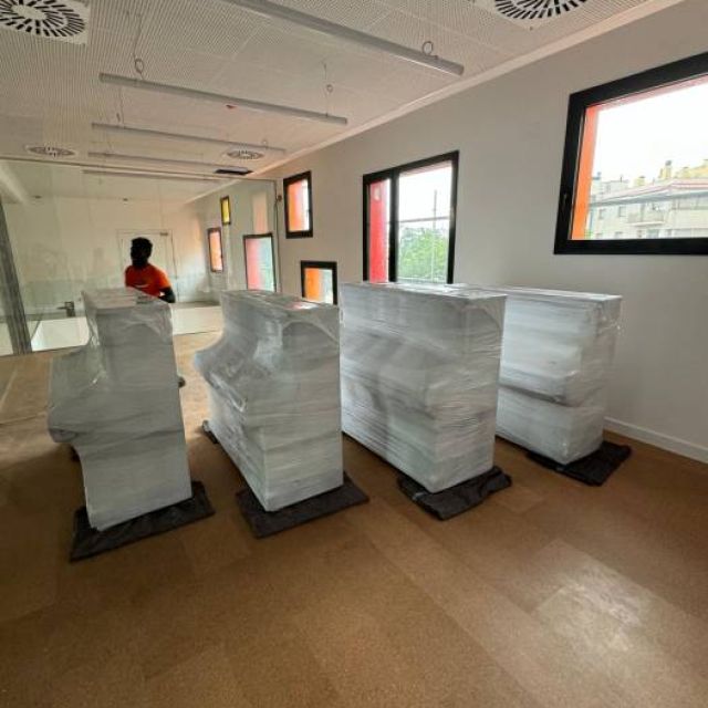 traslado de varios pianos de pared de empresa de musica, recien embalados y a espera de ser asegurados y encajados para un traslado seguro