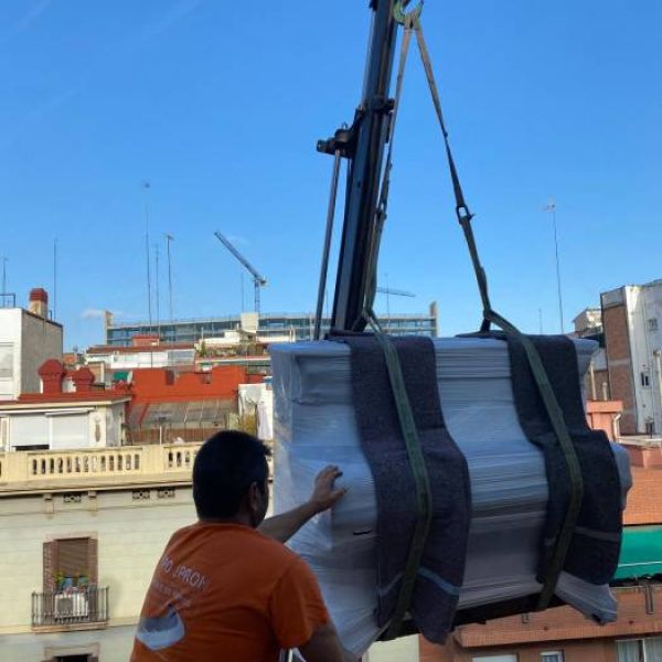 Piano gestionado por un operario desde el balcon donde esta llegando la grua con el piano